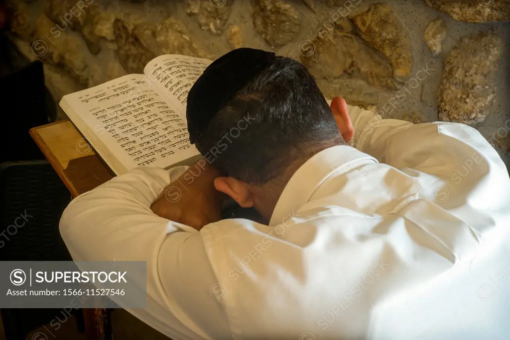 Closeup of a jewish unrecognizable man seen from behind, praying with his open prayer book in the synagogue in Wailing Wall Western Wall Plaza, Jewish...