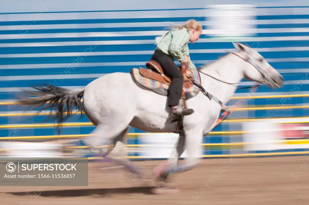 Motion blur of a young cowgirl riding fast during barrel racing, Airdrie Rodeo, Airdrie, Alberta, Canada.