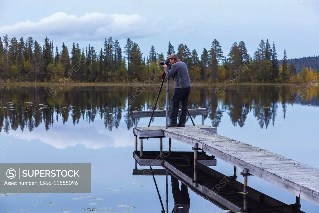 Photographer standing on a landing stage and taking photo in Gällivare, Swedish lapland.