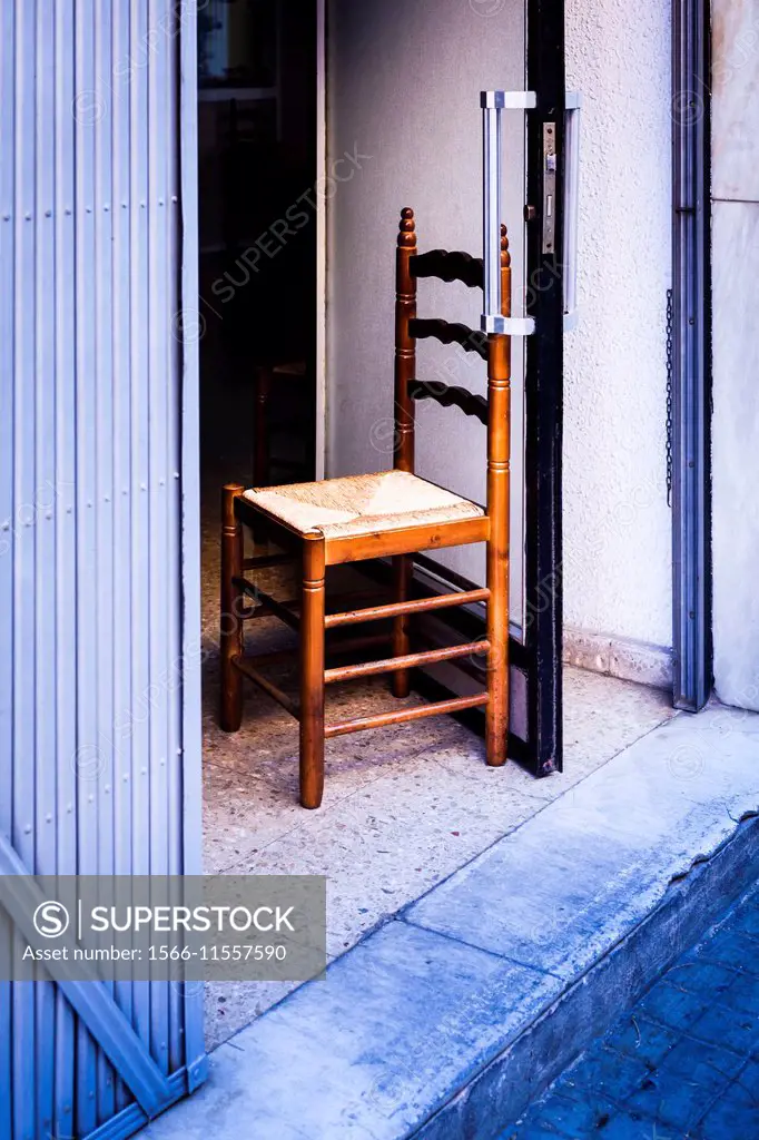 Chair holding a door in a bar in the neighborhood of Torrefiel, Valencia, Spain, Europe.