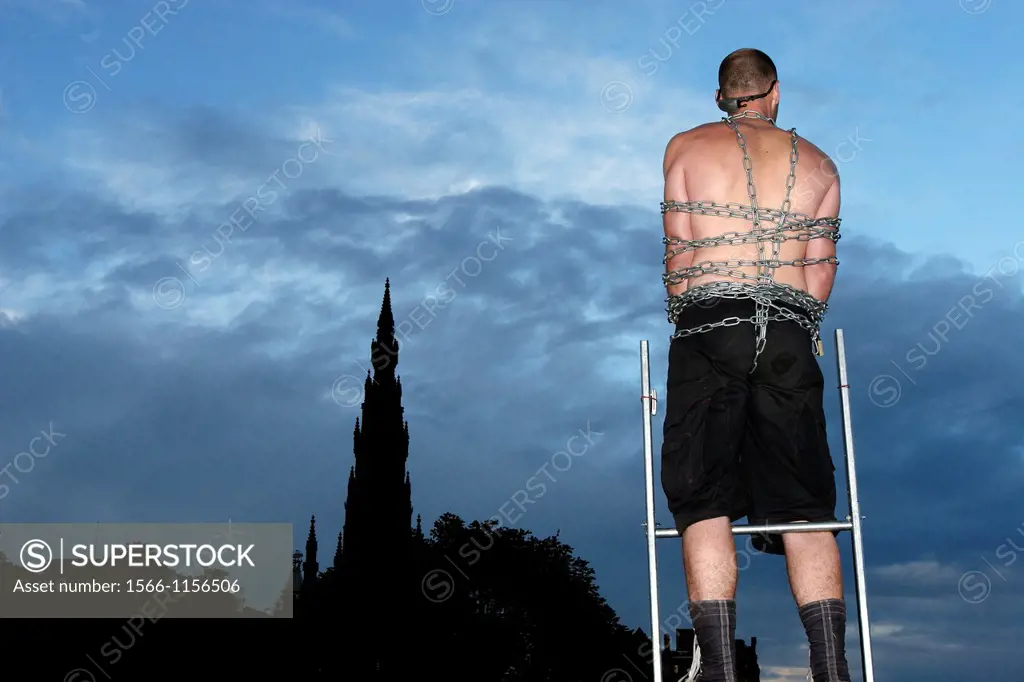 Acrobat tied with chains acting in Princes street of Edinburgh, infront of the scott monument, during the 2007 editon of the fringe festival