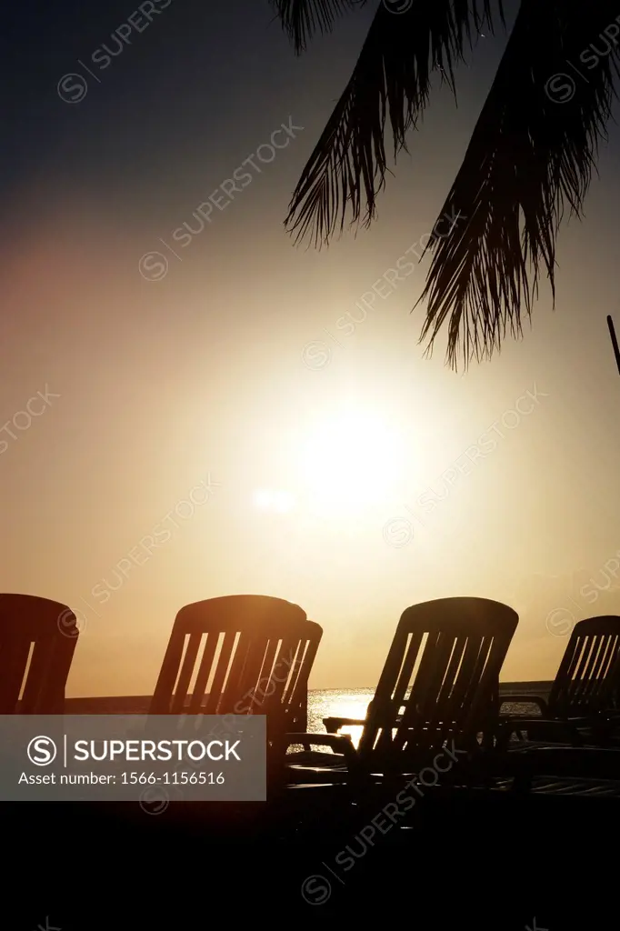 Sunset in playa Ancon beach with some sun lounger and palm tree leaves in the front of the sea