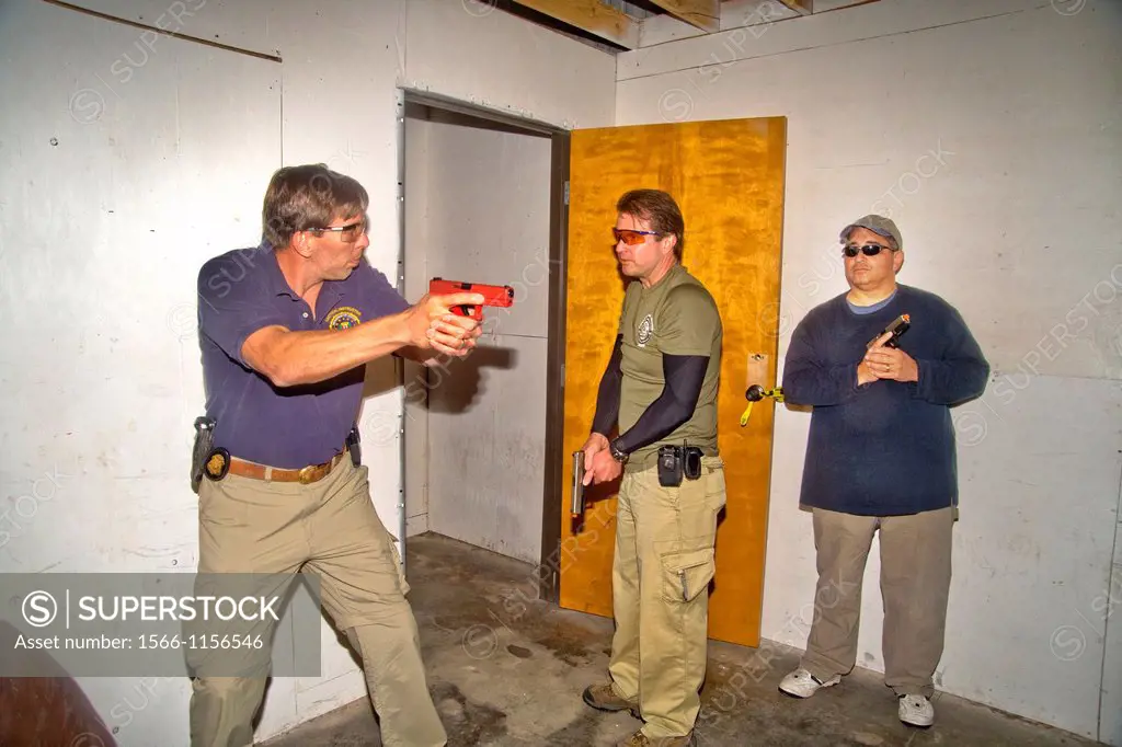 Under the eye of an instructor, law enforcement agents practice entering or ´breaching´ a room with weapons at a Southern California ´simunitions´ sim...