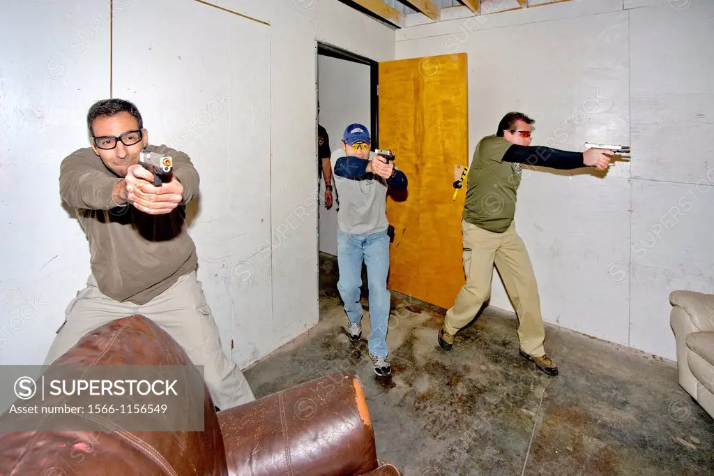 Under the eye of an instructor, law enforcement agents practice entering or ´breaching´ a room with weapons at a Southern California ´simunitions´ sim...