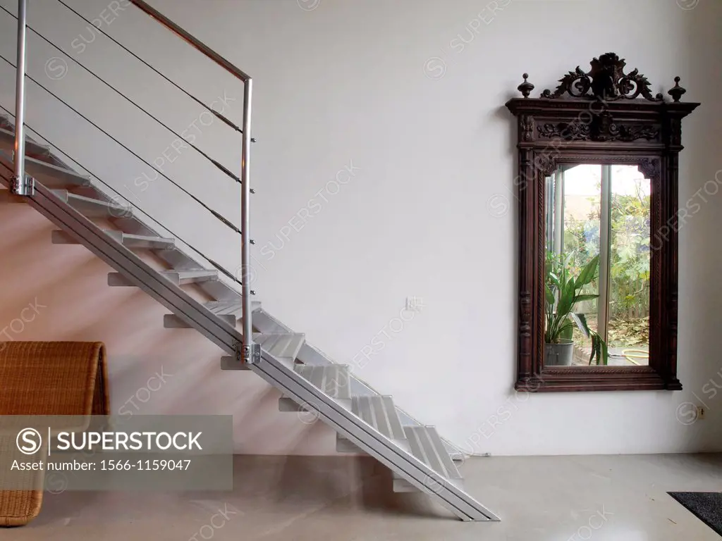 Big wooden mirror. Metallic staircase. Cane armchair. Interior designed by Gabriel Rodriguez.
