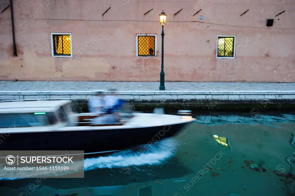 A speed boat sails over a canal in the Arsenale, Venice, Italy