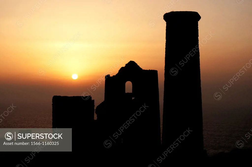 an old cornish tin mine with the setting sun as a background