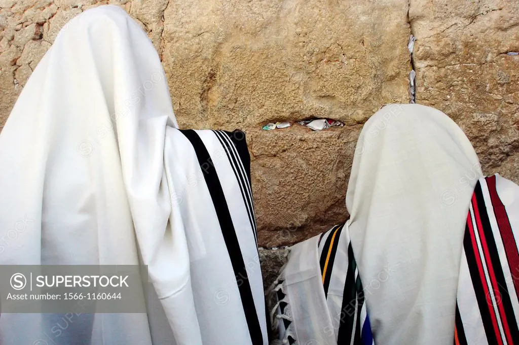 Jewish Men are praying wrapped in talit at the western wall in the old city in Jerusalem, Israel