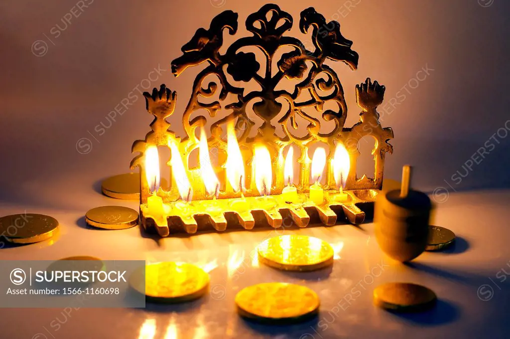Photo of a dreidel spinning top, gelts candy coins and an ancient brass menorah for the Jewish holiday of Hanukkah