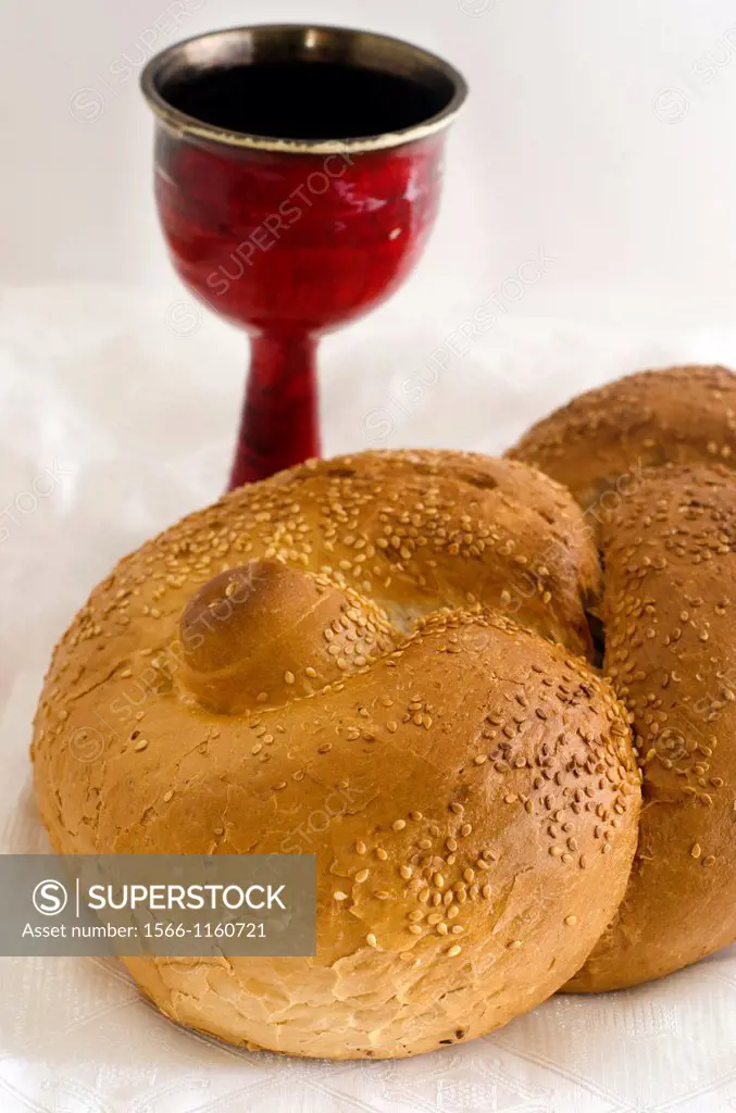 A concept photo of challah bread for the Jewish observance of Shabbat with a glass of wine in the background