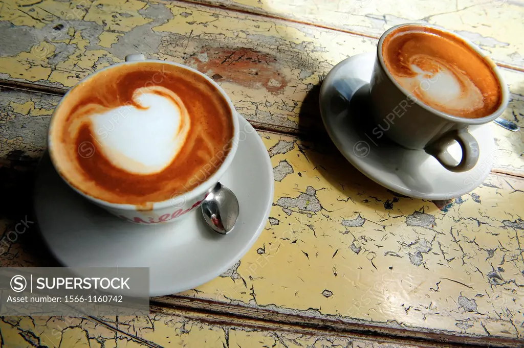 Cups of hot flat white coffee drinks on an old wooden table in a cafe