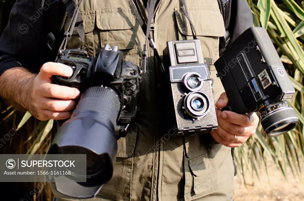 A wildlife photographer wearing many cameras and a photography vest