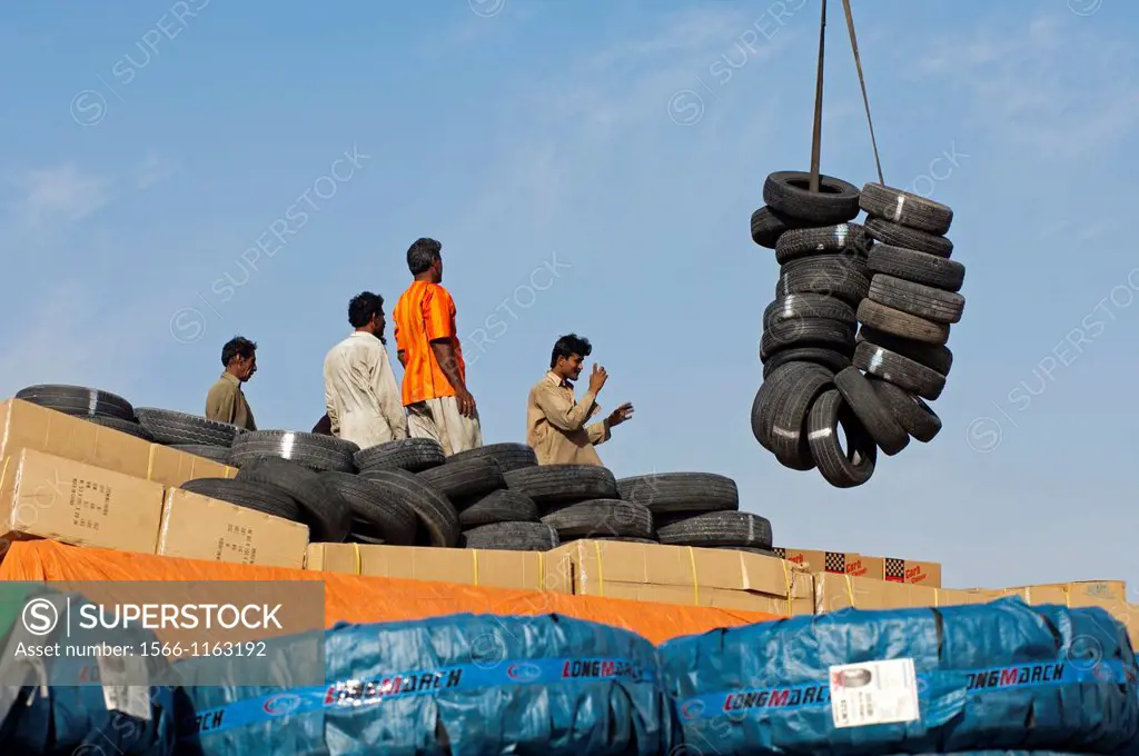 Docker directing a crane load of used tyres in the port of Dubai, United Arab Emirates