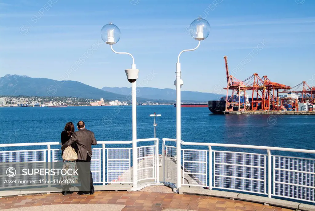 a couple enjoys the view of North Vancouver and the port from Canada Place in Vancouver, BC, Canada