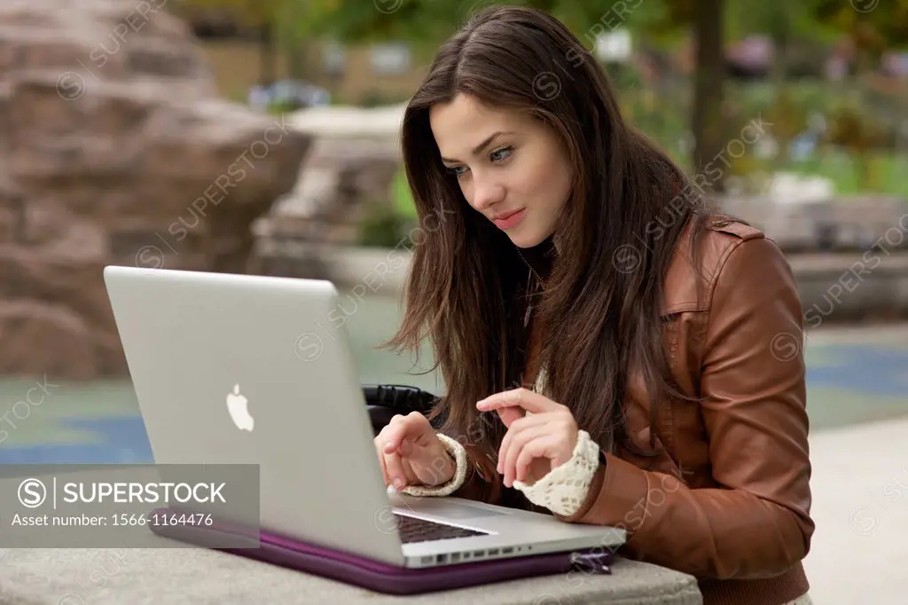 Young caucasian girl using MacBook Pro laptop outdoor