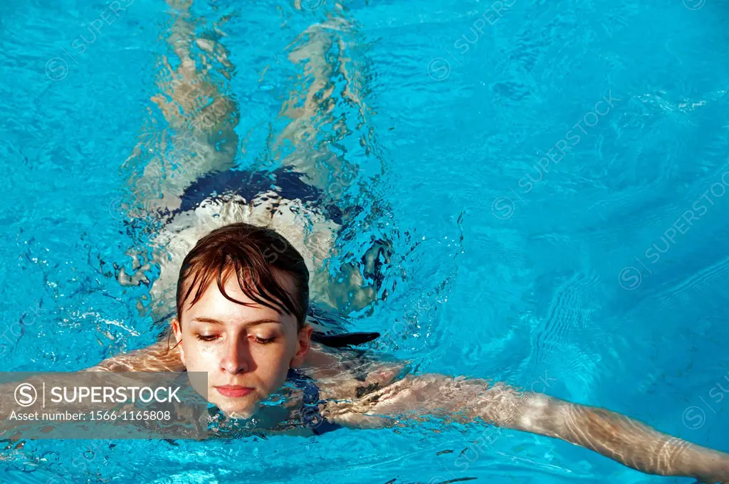 young woman swimmng in a swimming pool, close-up for face, front view