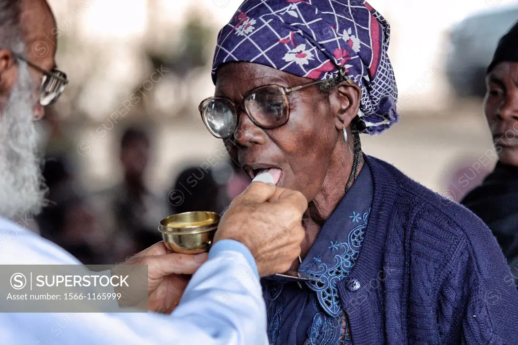 Older woman taking communion from priest in Chalucuane, Mozambique