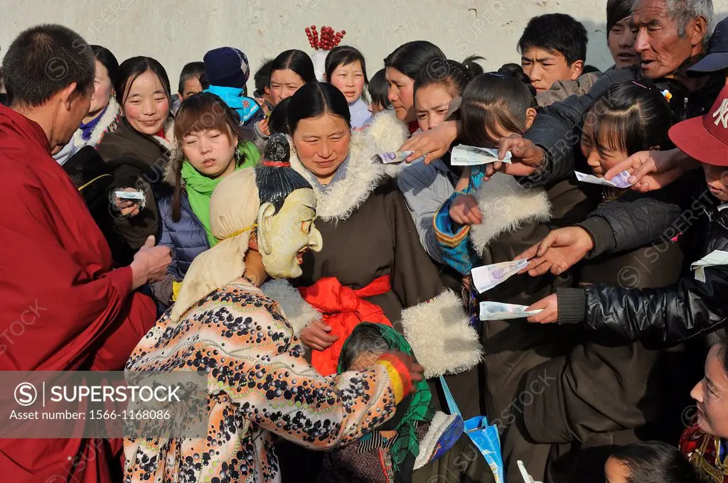 China, Qinghai, Amdo, Tongren Rebkong, Monastery of Gomar Guomari Si, Losar New Year festival, Atsara clown collecting money offerings from the audien...