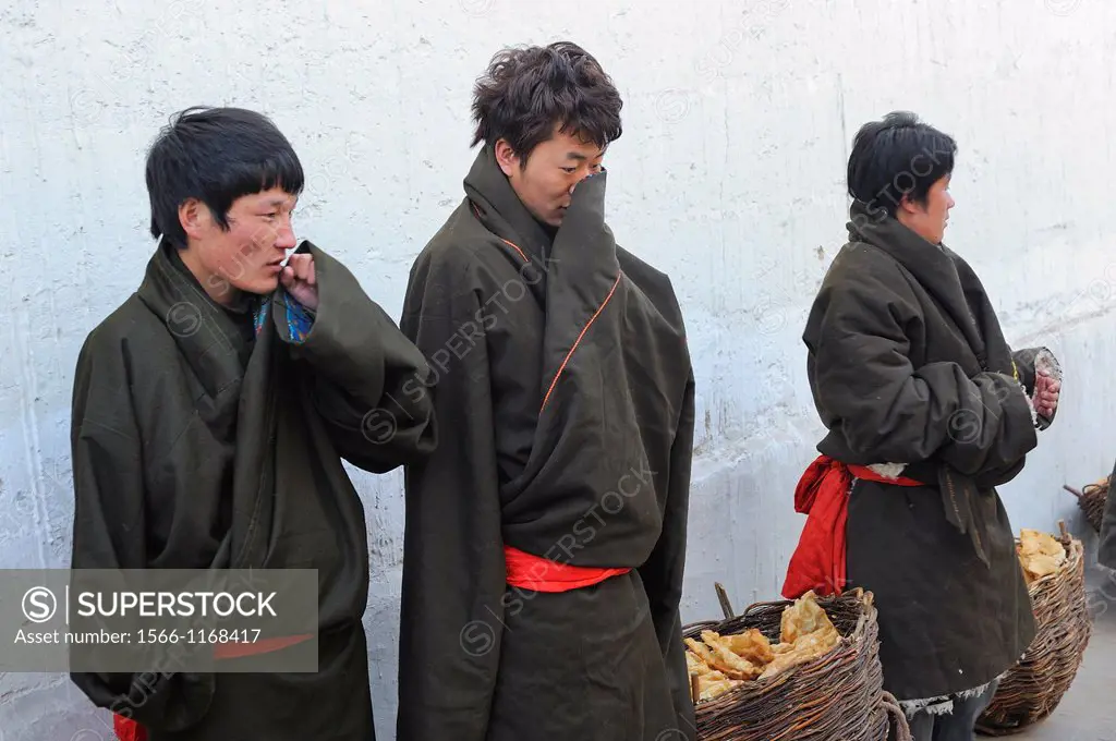 China, Qinghai, Amdo, Tongren Rebkong, Monastery of Gomar Guomari Si, Losar New Year festival, Breakfast bearers warming up in the cold morning
