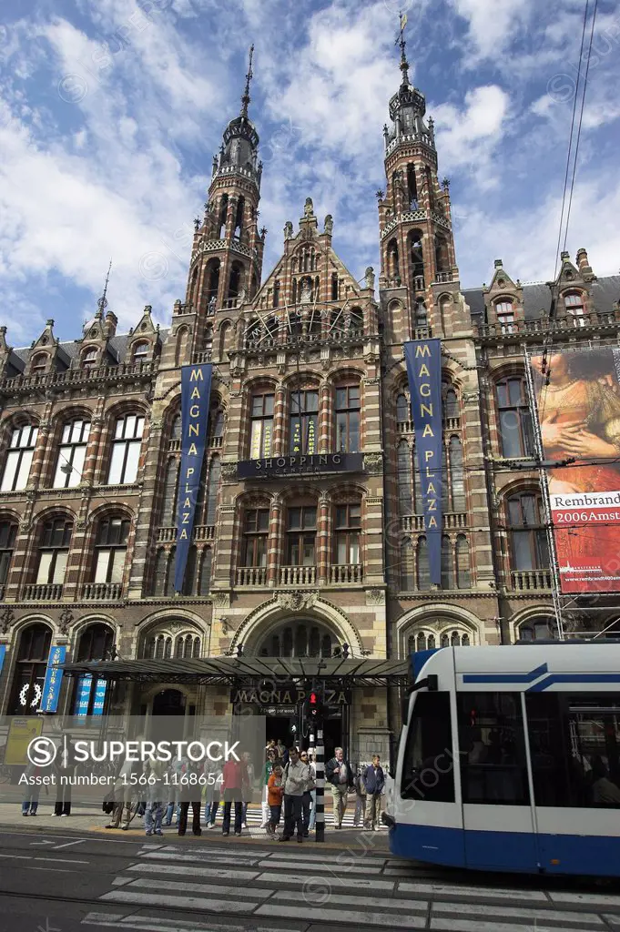 Tram passes former post office the Magna Plaza shopping centre in converted building Amsterdam The Netherlands