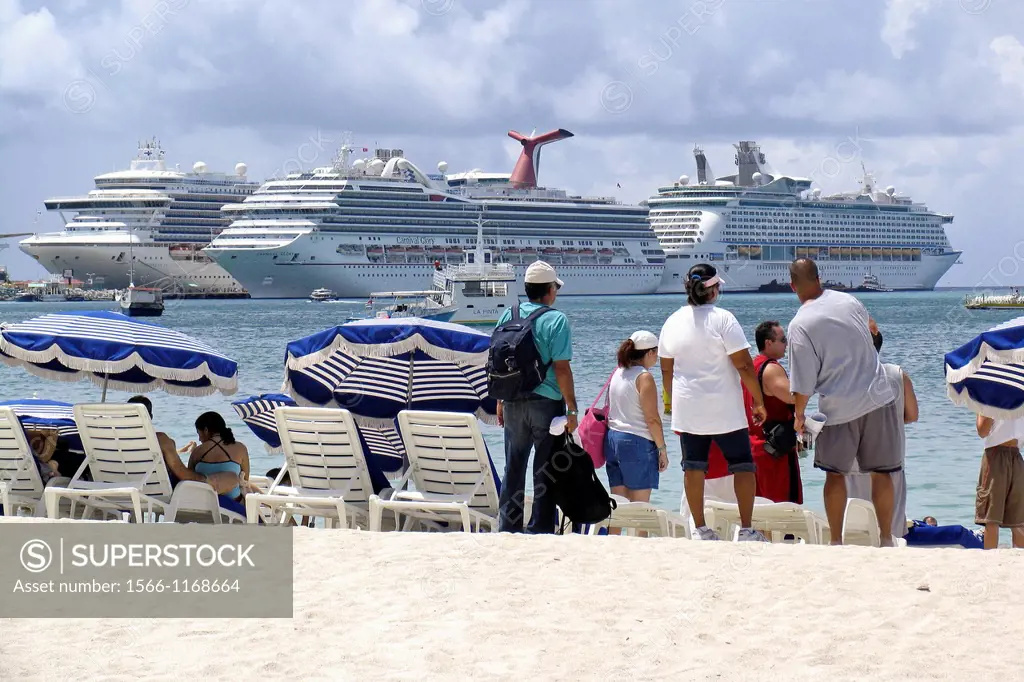 Visitors on Great Bay beach Philipsburg with three cruise ships docked in background St Maarten