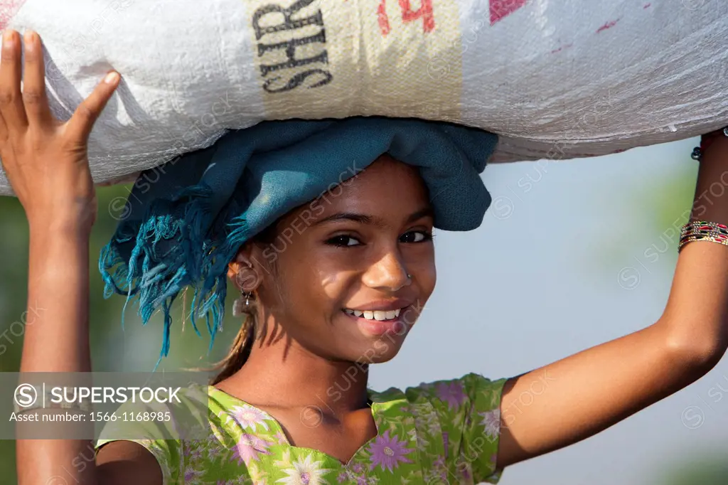 Young woman walking with large bundle on head India