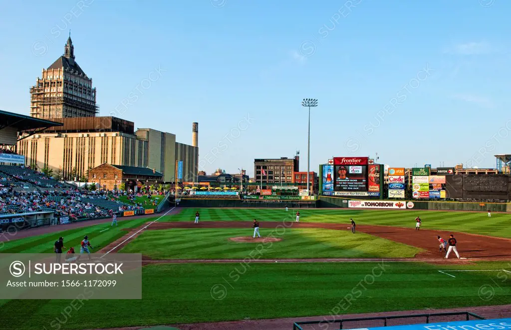 Night professional baseball game at Frontier Field Stadium in Rochester New York with city and Kodak in background and Rochester Red Wings playing