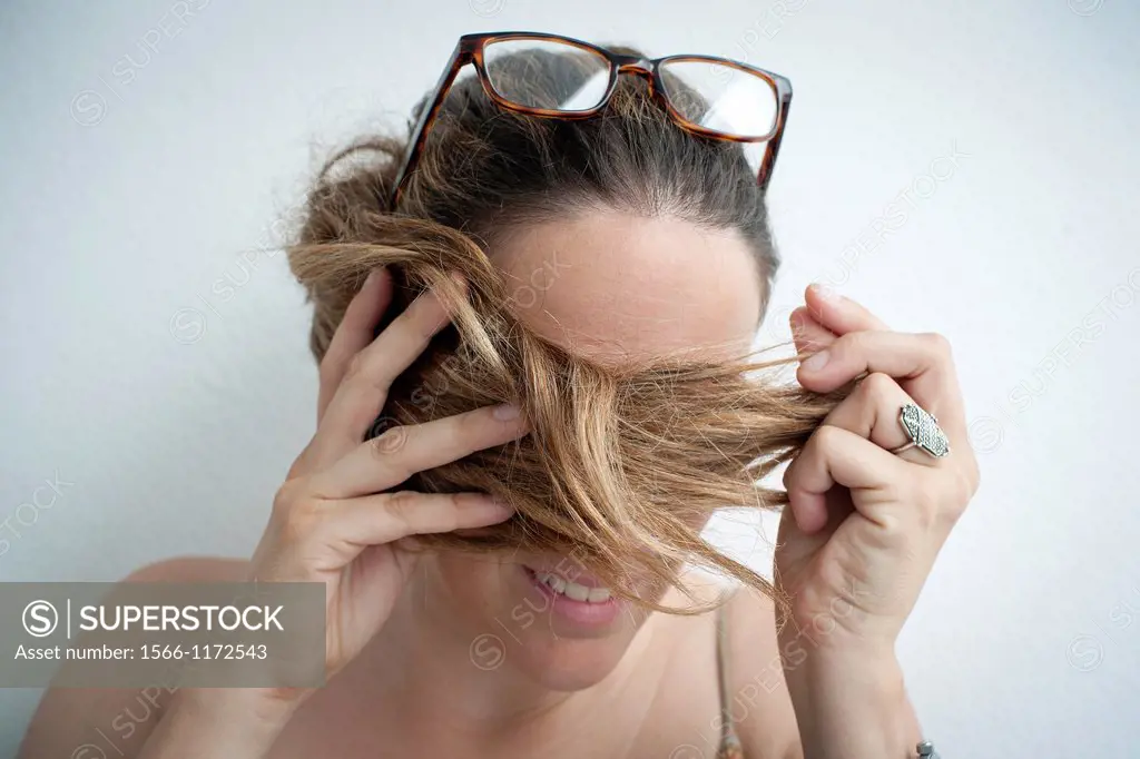 Retrato de mujer joven con gafas en la cabeza y pelo tapando los ojos, Portrait of young woman with sunglasses on her head and hair covering eyes,