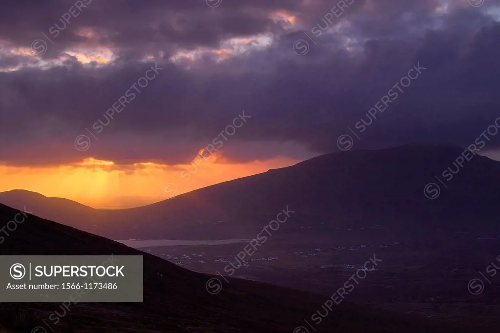 Sunset through stormy clouds, Achill Island, County Mayo, Ireland  Slievemore is seen on the right and Keel village can be seen in the valley