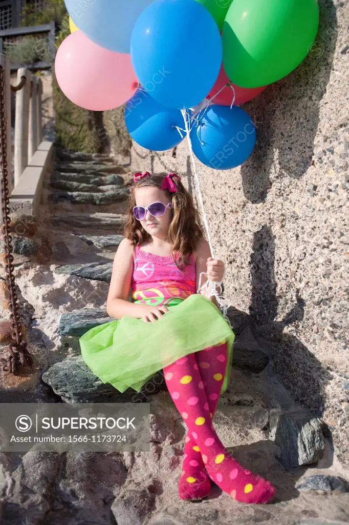 one little girl sitting on stone steps holding balloons