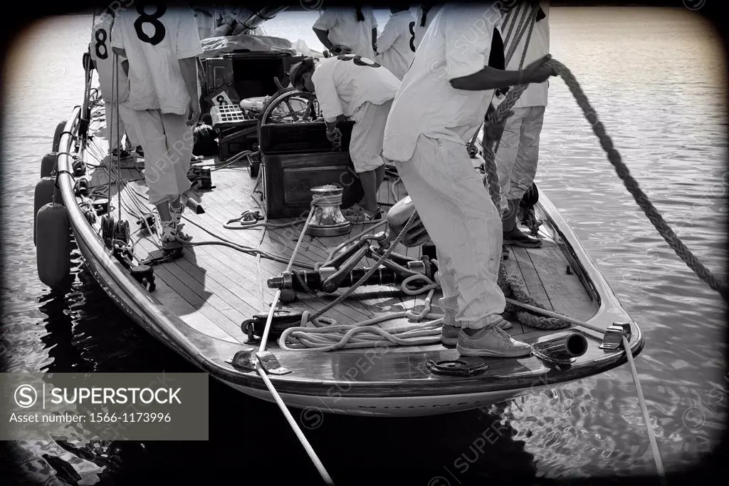 primer plano de marineros amarrando un barco de epoca de regatas, forefront of sailors tying a vintage racing yacht,
