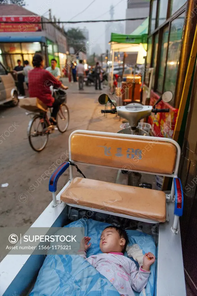 A baby left to sleep alone in the back of a motorcycle wagon