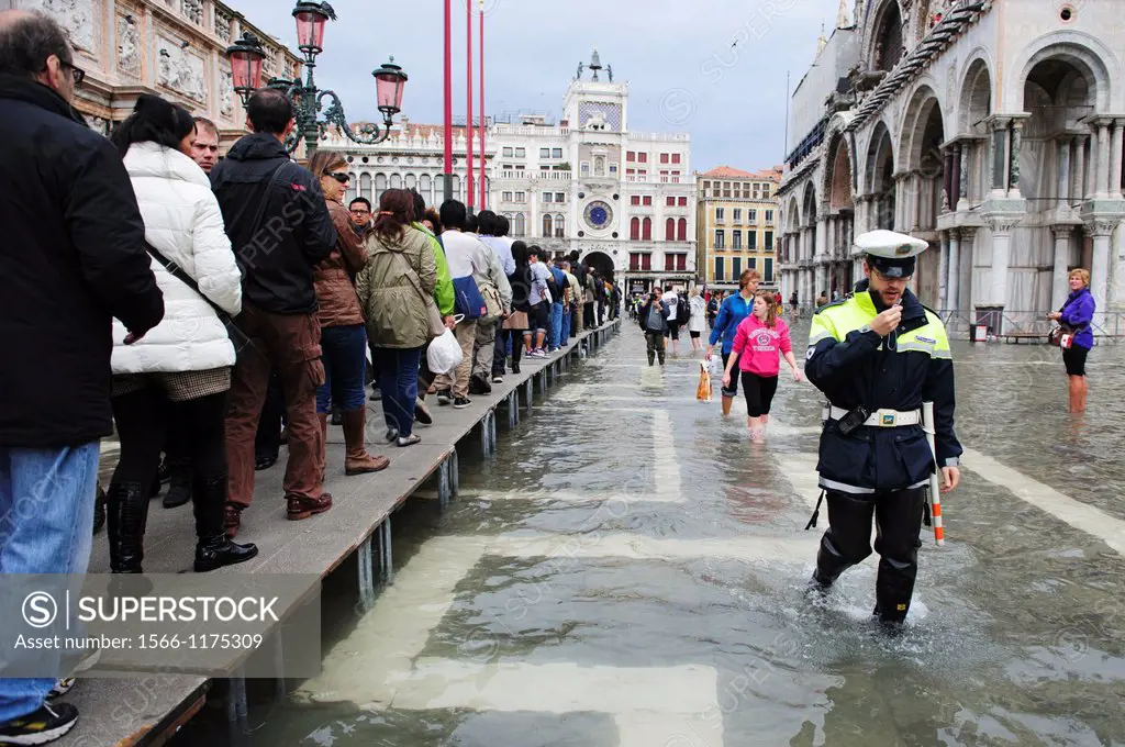 A policeman tries to avoid people stopping in the provided walk paths during the first day of the ´Acqua Alta´ season in Venice