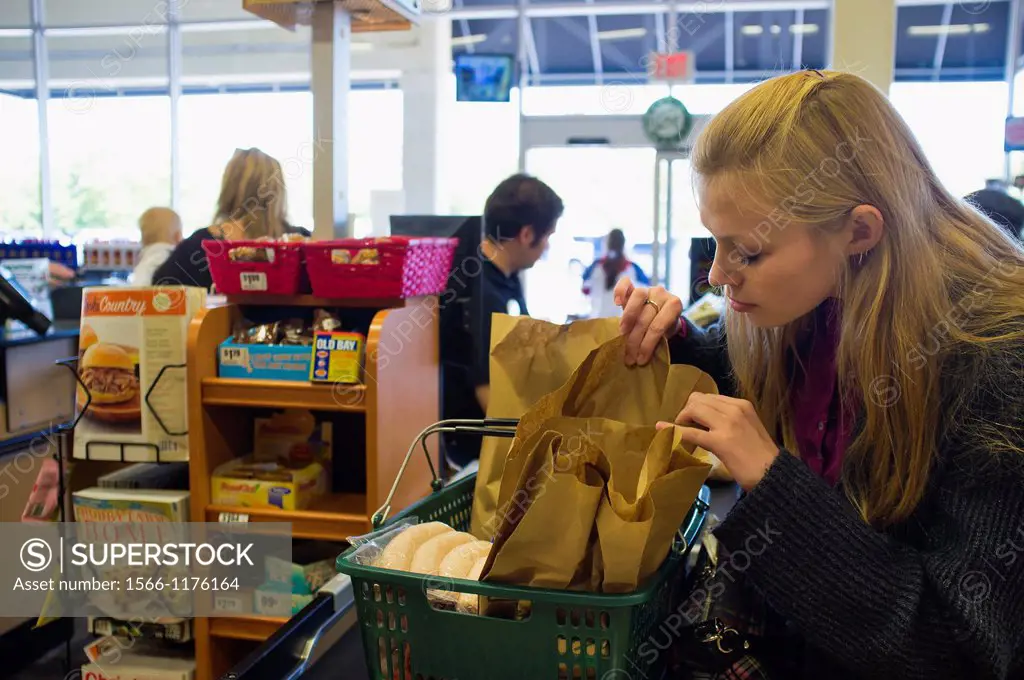 Young woman checking out at cash register in american supermarket