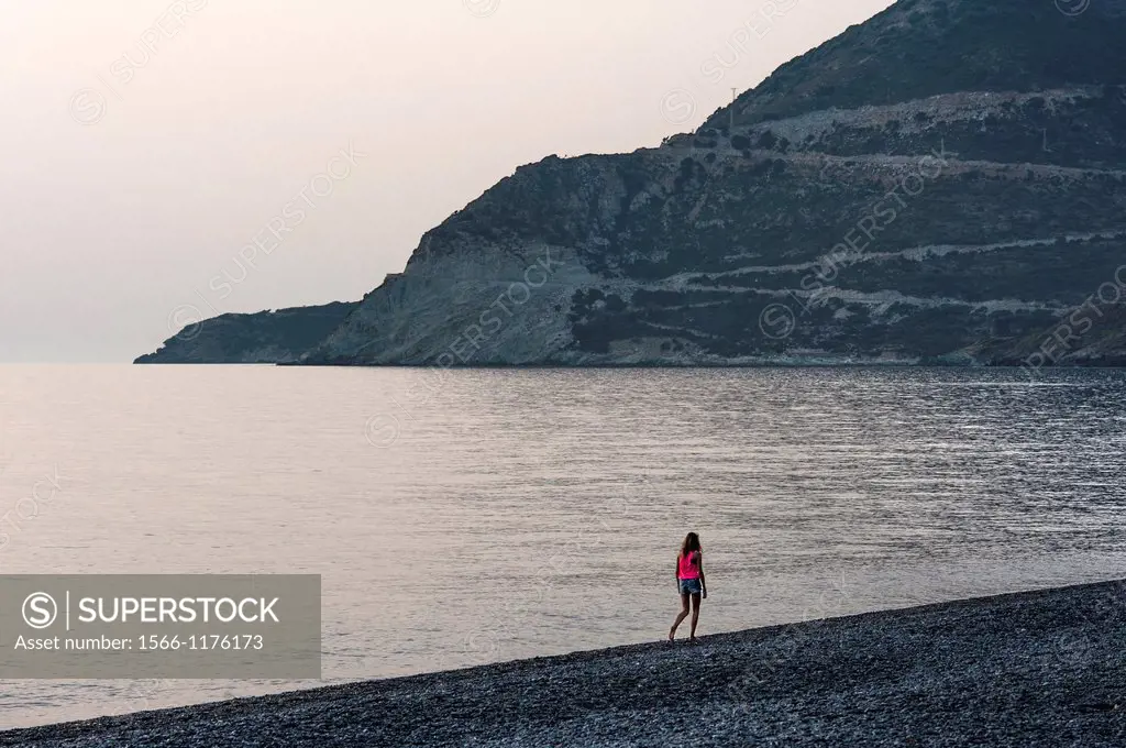 Europe, France, Corse, Haute Corse 2B, Cap Corse. Nonza. Young girl walking on the black pebbles beach.