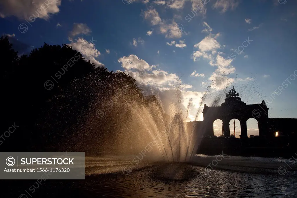 Fountain and Arch at Parc du Cinquantenaire Jubelpark, in Dutch, pictured as the sun sets and shines through the water