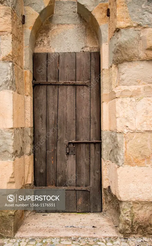 An ancient wooden door is set in a stone archway in Marostica, Italy