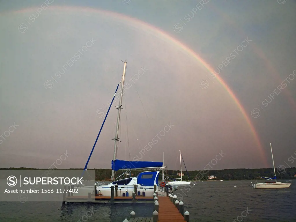 A double rainbow appears over Martha,s Vinyard, Massachusetts on a stormy day  Boats are moored in Laguna Pond, an Atlantic Ocean inlet