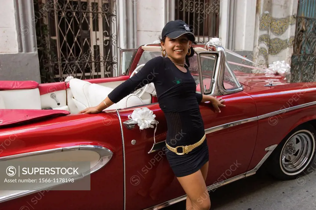 Girl standing in front of an old Cuban car