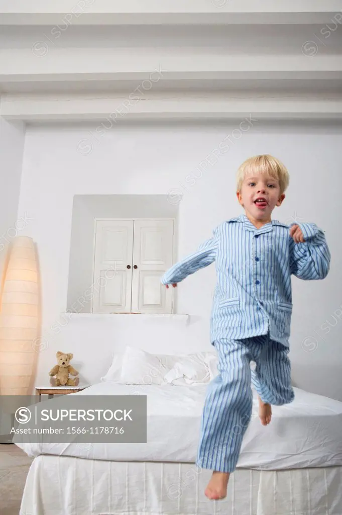 Four year old boy jumping off the bed