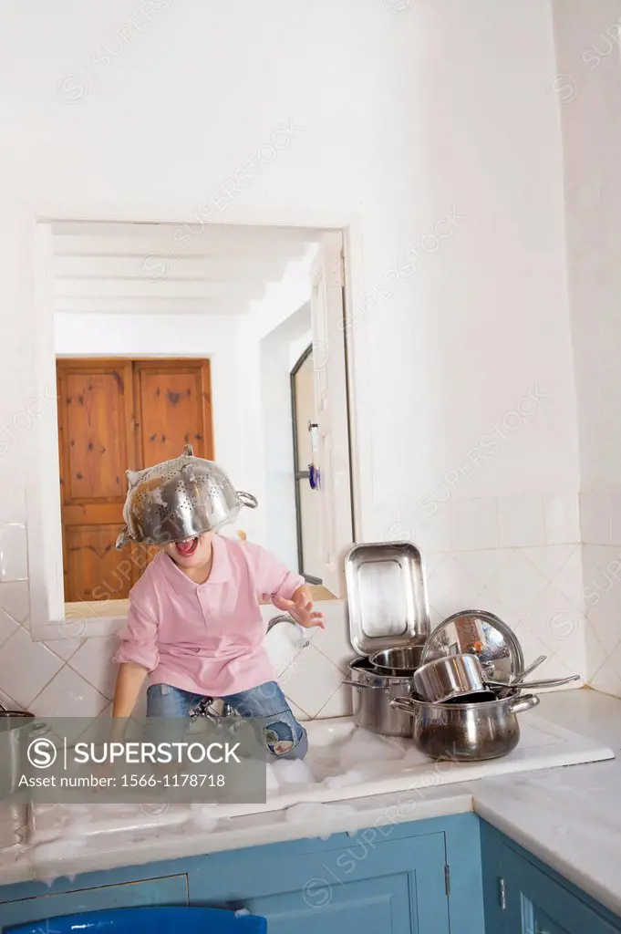 Four year old boy playing in the kitchen sink