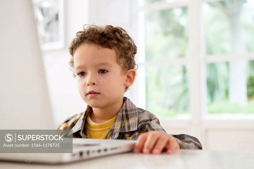Four year old boy playing games on a laptop