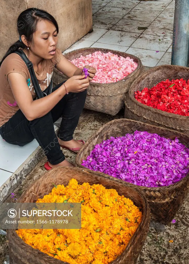 Woman selling flowers for decorating religious offerings, at the market in Ubud, Bali, Indonesia