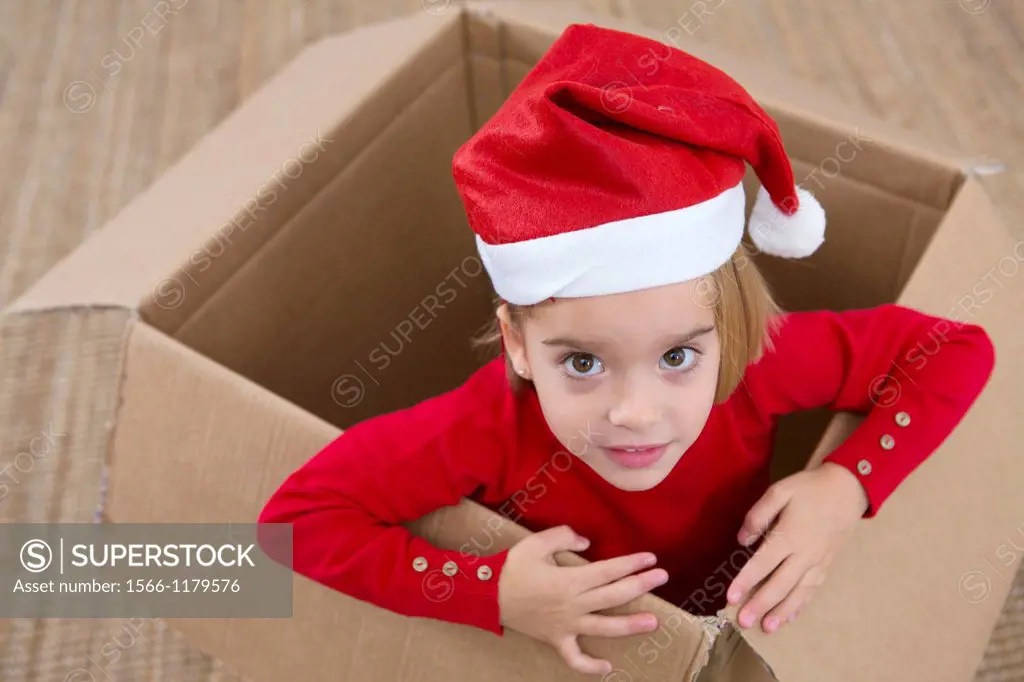 Four year old girl playing in a cardboard box at Christmas