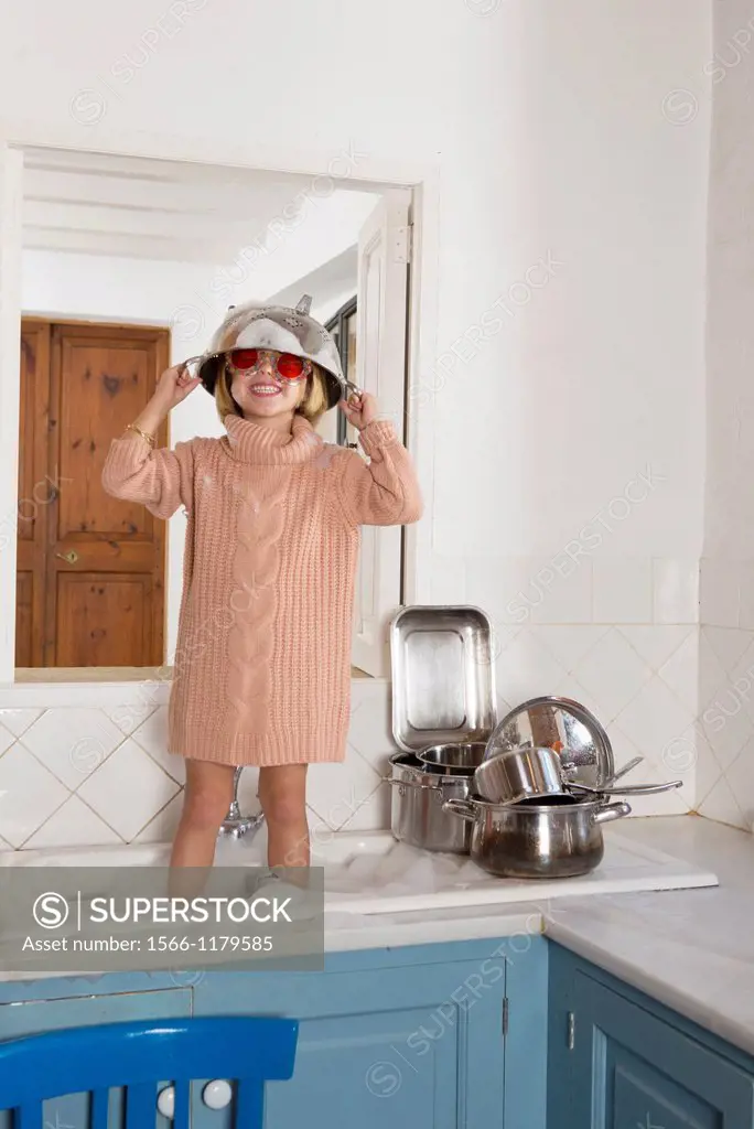 Four year old girl playing in the kitchen sink