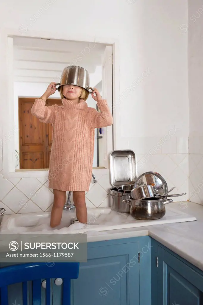 Four year old girl playing in the kitchen sink