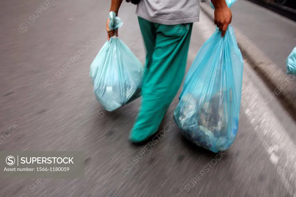 man carrying full plastic rubbish bags in street road in city town
