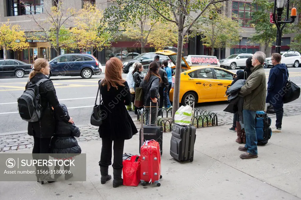 People with luggage in Battery Park City in the Zone A evacuation zone line up at a taxi stand prior to of Hurricane Sandy, in New York In advance of ...