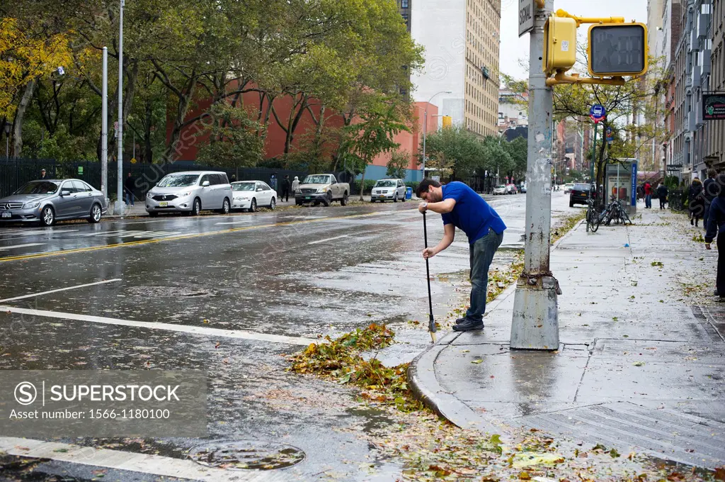 A man cleaning storm debris from the high winds of Hurricane Sandy away from a storm drain seen in the New York neighborhood of Chelsea Hurricane Sand...