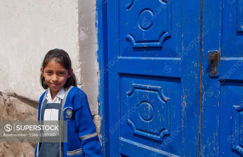 School child aged 10 in uniform and blue door in small town of Pisaq Peru